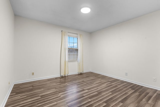 unfurnished room with dark wood-type flooring