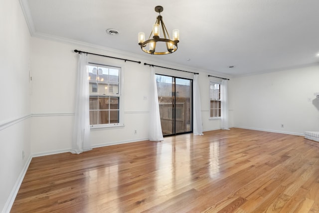 spare room featuring crown molding, a notable chandelier, and light hardwood / wood-style floors