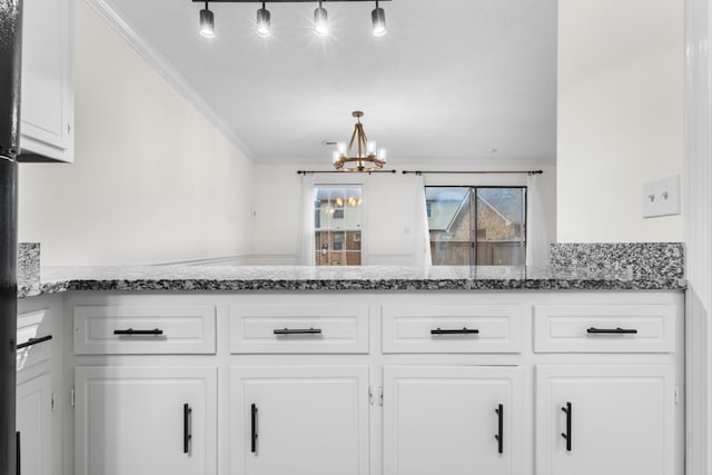 kitchen with decorative light fixtures, white cabinetry, dark stone counters, ornamental molding, and a notable chandelier