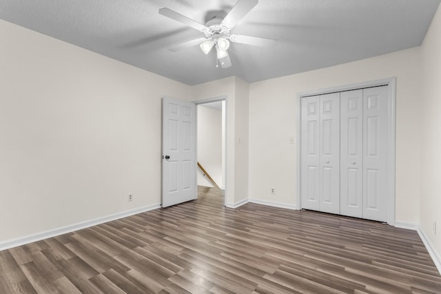 unfurnished bedroom with ceiling fan, a closet, dark hardwood / wood-style floors, and a textured ceiling