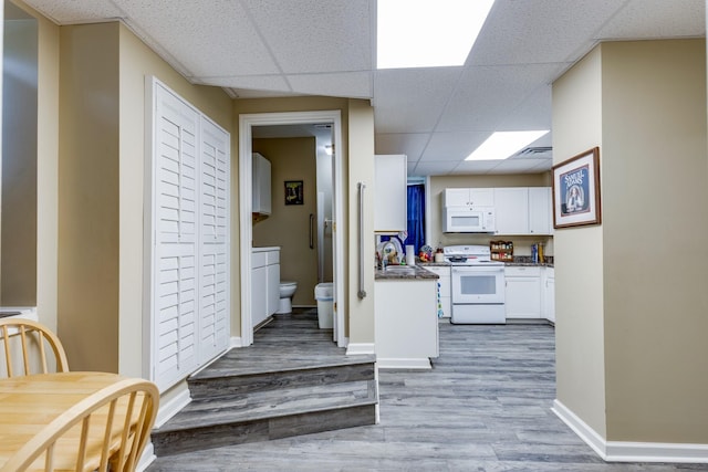 corridor with a paneled ceiling, wood-type flooring, and sink