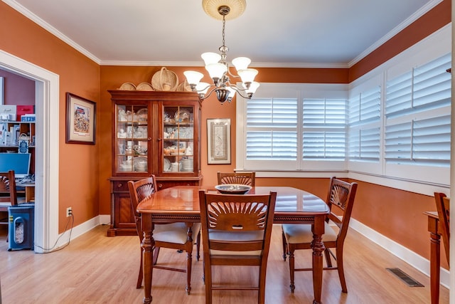 dining area with a notable chandelier, ornamental molding, and light wood-type flooring