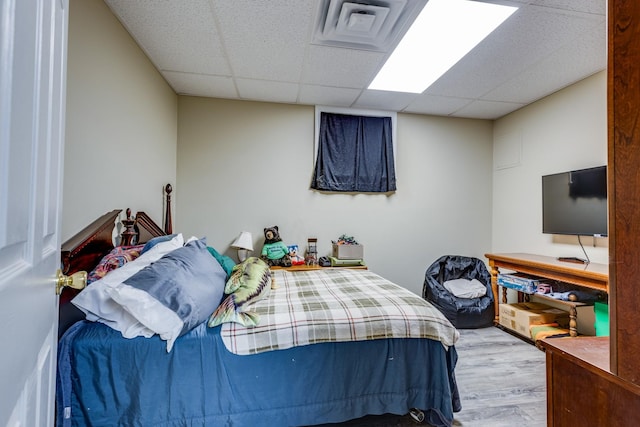 bedroom featuring a paneled ceiling and light wood-type flooring