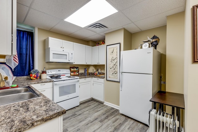 kitchen featuring white cabinetry, light hardwood / wood-style flooring, radiator heating unit, white appliances, and a drop ceiling