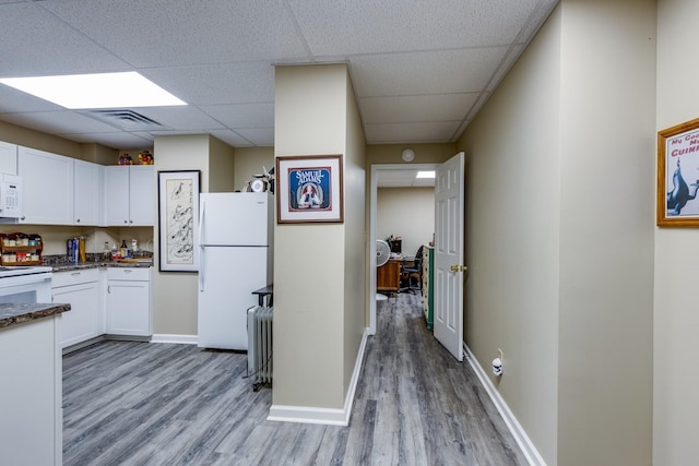 kitchen featuring a drop ceiling, white cabinets, white appliances, and light hardwood / wood-style floors