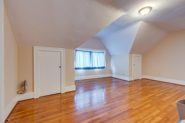 additional living space featuring hardwood / wood-style flooring and vaulted ceiling