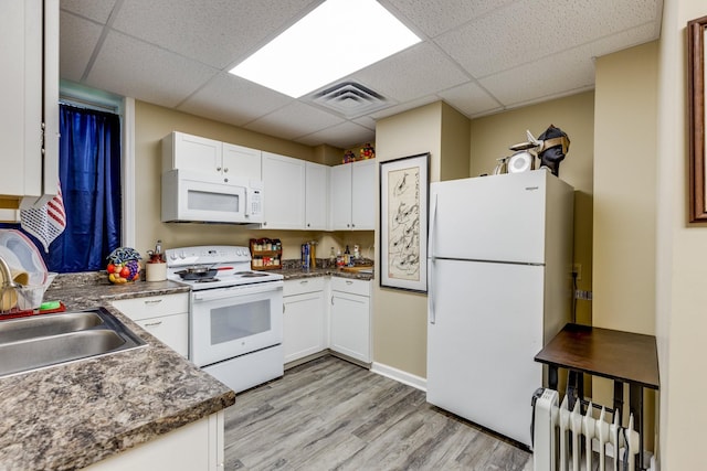 kitchen with radiator, white appliances, light hardwood / wood-style floors, white cabinets, and a drop ceiling