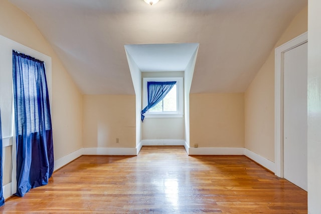 additional living space featuring vaulted ceiling and light wood-type flooring