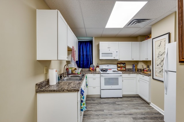 kitchen featuring sink, white appliances, light hardwood / wood-style floors, white cabinets, and a drop ceiling