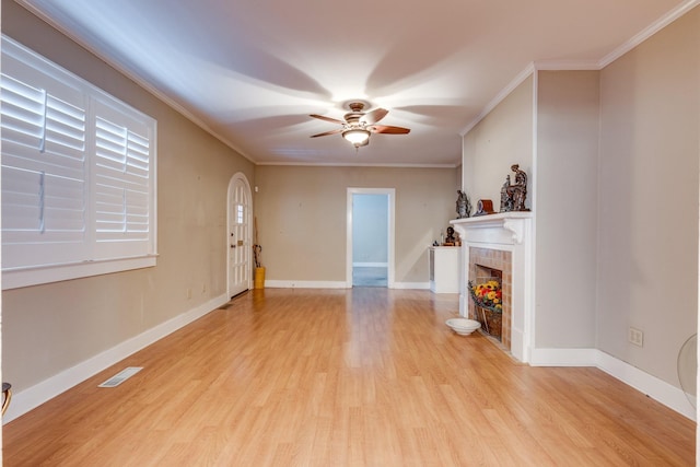 unfurnished living room with crown molding, ceiling fan, a fireplace, and light wood-type flooring