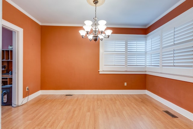 empty room with ornamental molding, hardwood / wood-style floors, and an inviting chandelier