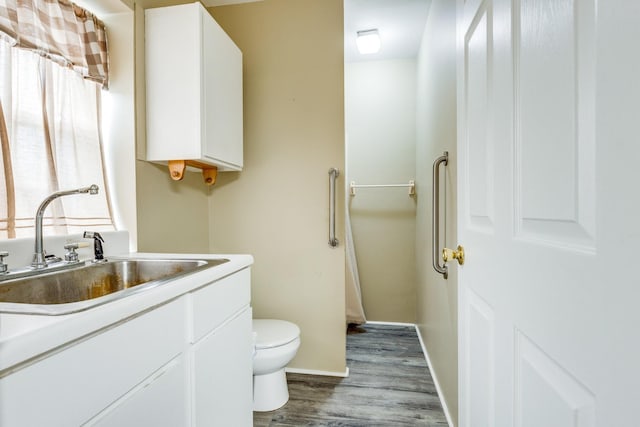 bathroom with wood-type flooring, toilet, and vanity