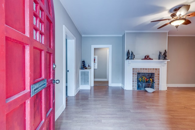 entrance foyer featuring crown molding, a fireplace, ceiling fan, and hardwood / wood-style flooring