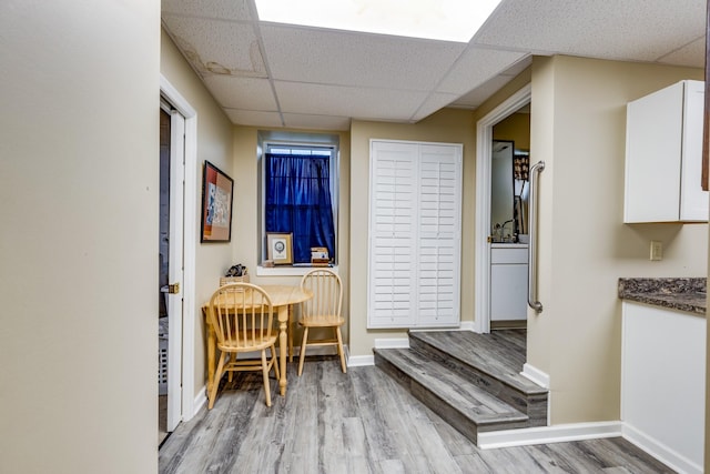 interior space with a drop ceiling and light wood-type flooring