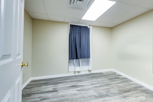 spare room featuring wood-type flooring and a drop ceiling