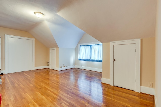 additional living space with hardwood / wood-style flooring and vaulted ceiling