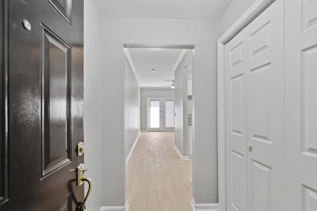 corridor with light hardwood / wood-style flooring and ornamental molding