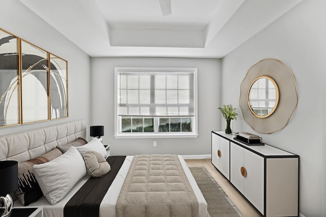 bedroom featuring a tray ceiling and light wood-type flooring