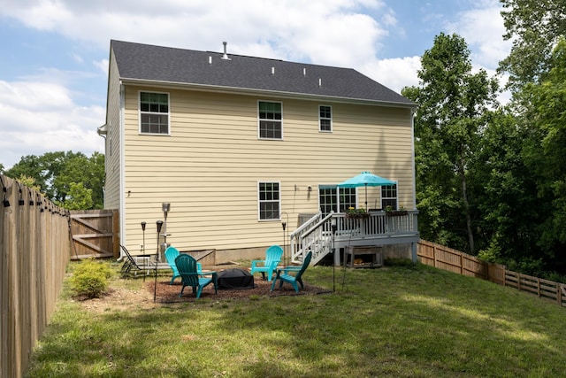 back of house with a yard, a deck, and a fire pit