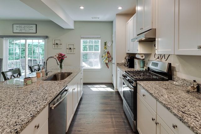 kitchen featuring appliances with stainless steel finishes, white cabinetry, sink, dark hardwood / wood-style flooring, and light stone countertops