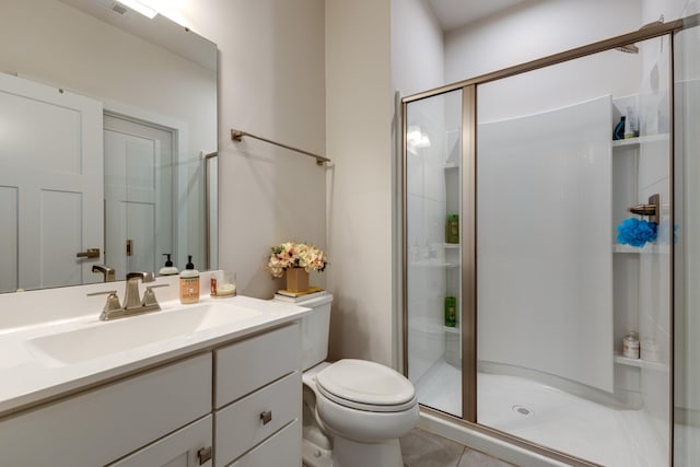 bathroom with vanity, a shower with shower door, tile patterned floors, and toilet