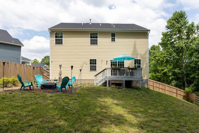 back of house featuring a yard, a deck, and a fire pit