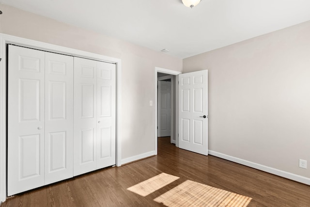 unfurnished bedroom featuring a closet and dark hardwood / wood-style floors