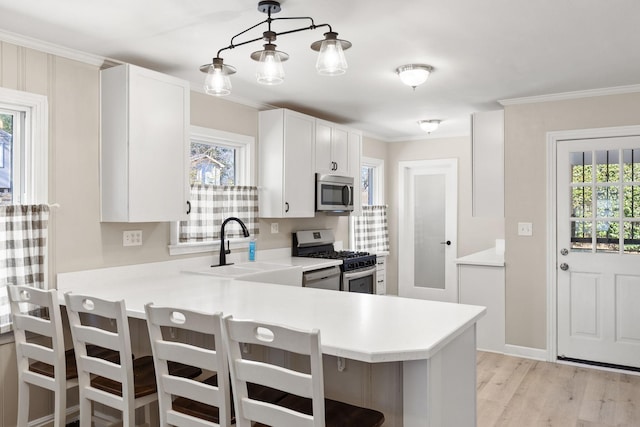 kitchen with appliances with stainless steel finishes, pendant lighting, white cabinets, and kitchen peninsula