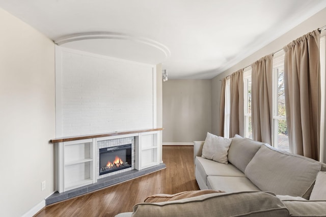 living room with a tile fireplace and dark hardwood / wood-style flooring