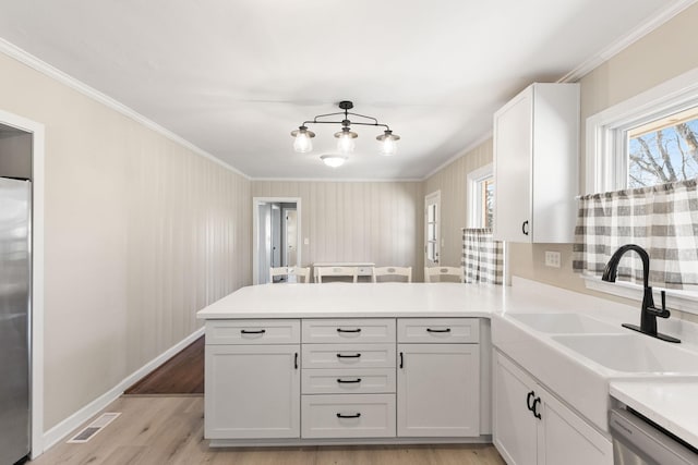 kitchen with appliances with stainless steel finishes, sink, white cabinets, and kitchen peninsula