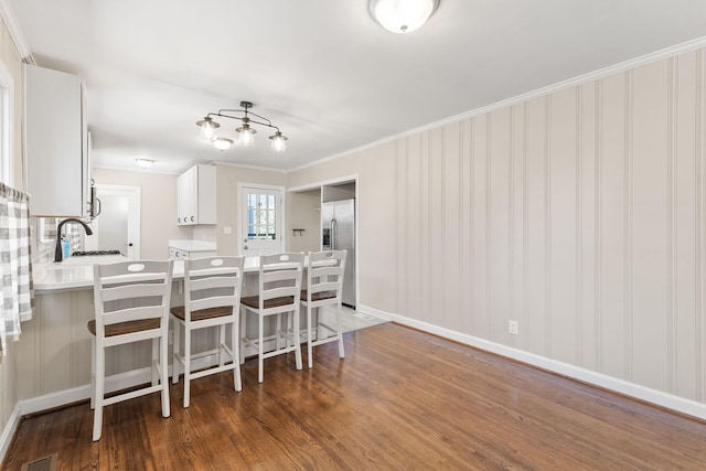 kitchen with stainless steel refrigerator with ice dispenser, sink, white cabinetry, dark hardwood / wood-style flooring, and kitchen peninsula