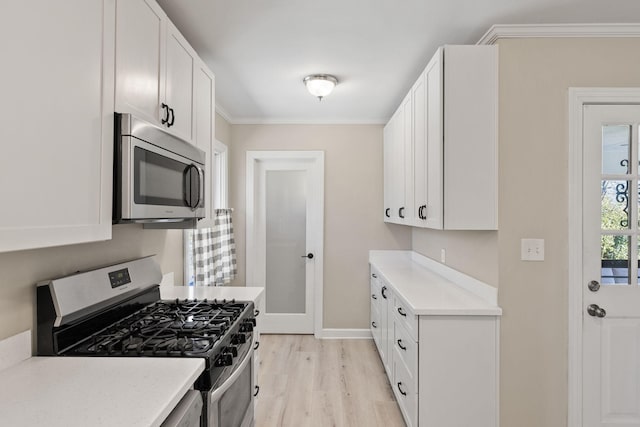 kitchen with crown molding, appliances with stainless steel finishes, white cabinets, and light hardwood / wood-style floors