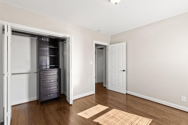 unfurnished bedroom with dark hardwood / wood-style floors and a closet