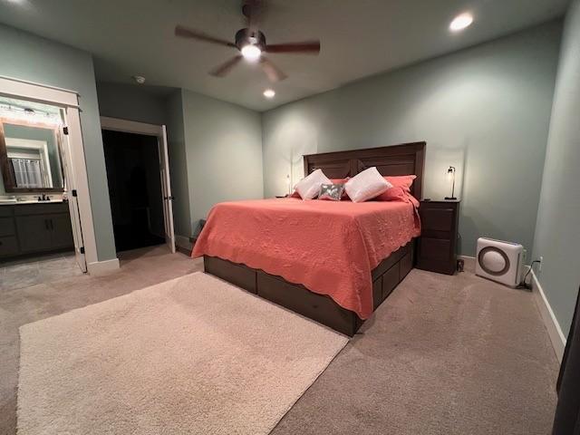 carpeted bedroom with ensuite bathroom and ceiling fan