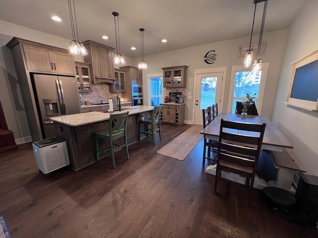 kitchen with hanging light fixtures, stainless steel refrigerator with ice dispenser, a large island, and a breakfast bar area