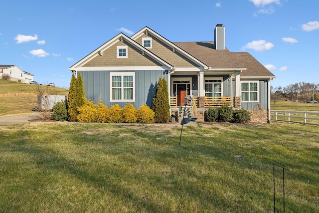 craftsman inspired home featuring a front yard, fence, board and batten siding, and a chimney