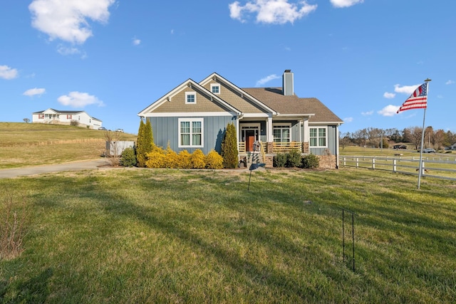 craftsman-style house with board and batten siding, a chimney, a front yard, and fence