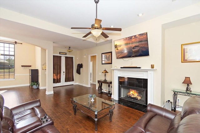 living room featuring ceiling fan, dark hardwood / wood-style floors, and a tile fireplace