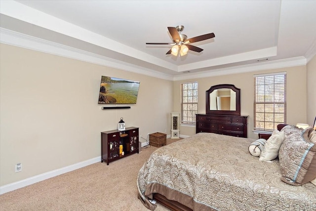 carpeted bedroom with a tray ceiling, ornamental molding, and ceiling fan