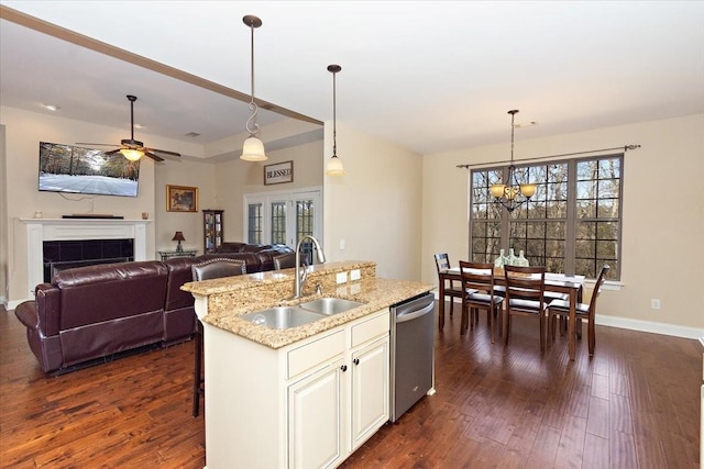 kitchen featuring sink, decorative light fixtures, dishwasher, and a center island with sink