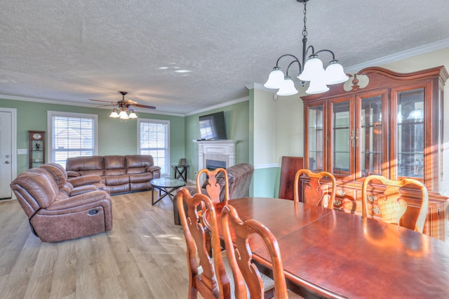 dining space featuring crown molding, light hardwood / wood-style flooring, a textured ceiling, and ceiling fan with notable chandelier