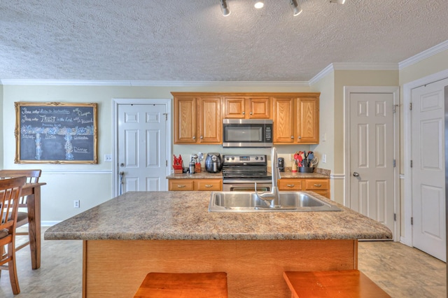 kitchen featuring crown molding, a breakfast bar, appliances with stainless steel finishes, a textured ceiling, and a center island with sink