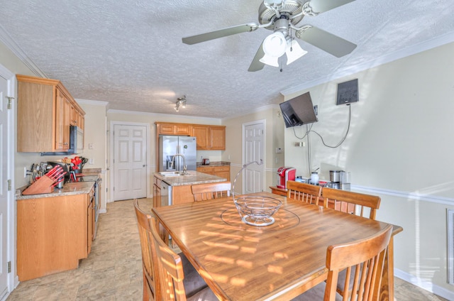 dining space with sink, ornamental molding, and a textured ceiling