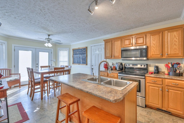 kitchen with sink, stainless steel appliances, an island with sink, a kitchen bar, and french doors