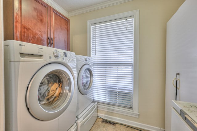 laundry area with ornamental molding, cabinets, and washing machine and clothes dryer