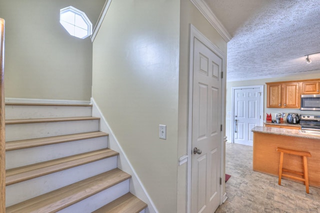 stairway featuring ornamental molding and a textured ceiling