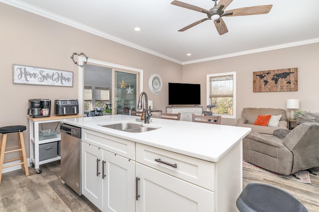 kitchen featuring sink, white cabinetry, ornamental molding, dishwasher, and an island with sink