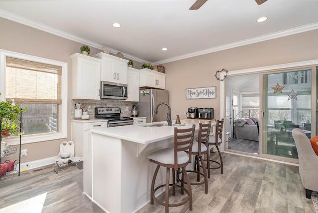 kitchen featuring sink, a breakfast bar area, stainless steel appliances, and white cabinets