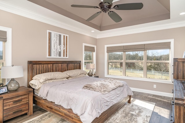 bedroom featuring ornamental molding, hardwood / wood-style floors, ceiling fan, and a tray ceiling