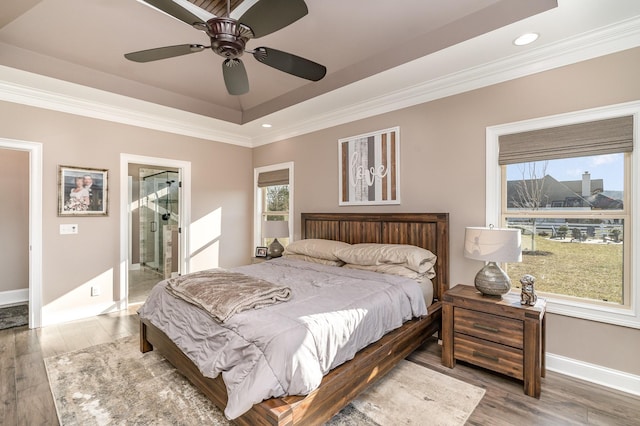 bedroom with crown molding, a tray ceiling, hardwood / wood-style floors, and multiple windows